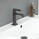 Stilfull badrumsinspiration med beige tvättställsskåp med innerskiva, överskåp, öppen hylla, ovalt spegel med belysning, matchande pendellampor, hylla under spegeln och vägghängd toalett. Väggar med ljusa, avlånga kakelplattor